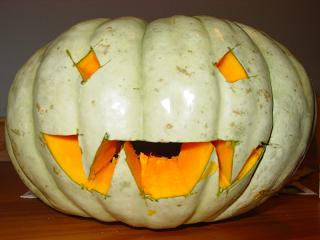 green pumpkin carved into goblin head